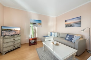 A cozy living room with a television, a sofa, a coffee table, and a lamp. - Cozy 1-room apartment in Hörnum - close to the beach & budget-friendly - (Hörnum (Sylt))
