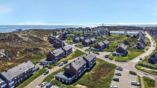 Un área residencial costera con casas modernas, una carretera y vista al mar.