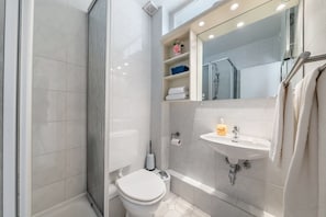A modern bathroom with a shower, toilet, and sink. - Cozy 1-room apartment in Hörnum - close to the beach & budget-friendly - (Hörnum (Sylt))