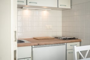 A compact kitchen with white cabinets, a wooden countertop, and a Bosch dishwasher. - Cozy 1-room apartment in Hörnum - close to the beach & budget-friendly - (Hörnum (Sylt))