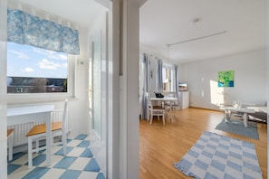 A modern apartment with a dining area, kitchen, and a view of the city. - Cozy 1-room apartment in Hörnum - close to the beach & budget-friendly - (Hörnum (Sylt))