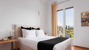 Ein modernes Schlafzimmer mit Bett, Nachttisch, einer Topforchidee und Blick auf eine Stadtkulisse durch ein großes Fenster.