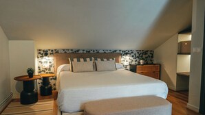 A bedroom with a large bed, a bedside table, a nightstand, a small table with a plant, and a wall with floral wallpaper. - Duplex with wonderful views, next to the historic center and walking trails. (Cazorla)
