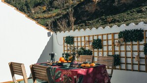 An outdoor dining area with a table set for two, surrounded by a white wall and a wooden fence. - Duplex with wonderful views, next to the historic center and walking trails. (Cazorla)