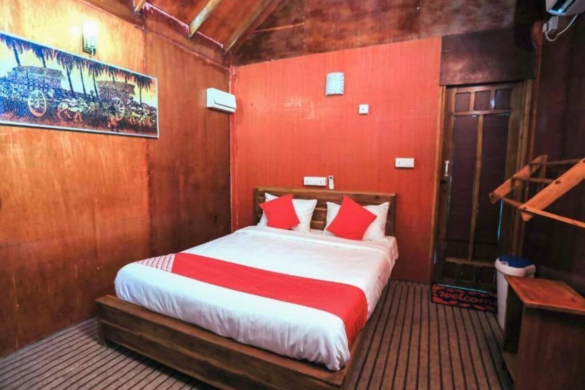 A wooden room with a bed, a painting on the wall, and a wooden staircase.