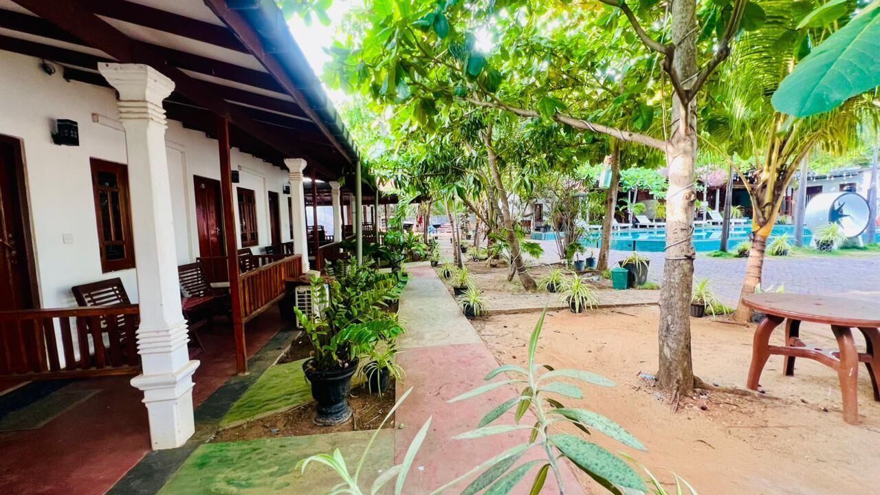 Un espace extérieur abrité, doté d’une rangée de bancs en bois, de plantes en pot et d’un chemin menant à une zone piscine.