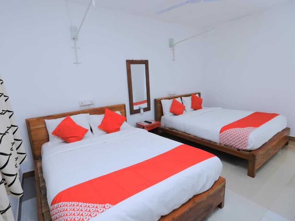Two single beds with wooden frames, white bedding, and red accents.