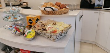 Monipuolinen aamiaisbuffet, jossa on tarjolla erilaisia ruokia ja lisukkeita.