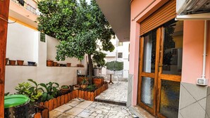 A courtyard with a stone floor, potted plants, and a wooden door. - Apartment for 4 in Quartu, near Poetto, Cagliari and nature, comfortable and complete (Quartu Sant'Elena)