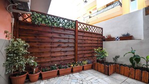 A courtyard with a wooden fence, potted plants, and a stone floor. - Apartment for 4 in Quartu, near Poetto, Cagliari and nature, comfortable and complete (Quartu Sant'Elena)