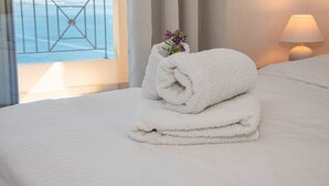 A neatly made bed with a folded white towel and a small vase with purple flowers. - Villa Anthula mit Pool und herrlichem Meerblick by Interhome (Kalami)