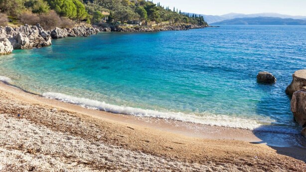 A coastal beach with clear turquoise waters, rocky shoreline, and a hilly backdrop. - Villa Anthula mit Pool und herrlichem Meerblick by Interhome (Kalami)