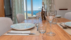 A dining table set with plates, glasses, and cutlery, overlooking a scenic view. - Villa Anthula mit Pool und herrlichem Meerblick by Interhome (Kalami)