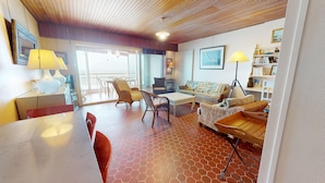 A cozy living room with a wooden ceiling, a dining table with chairs, a sofa, and a bookshelf. - Au Fil de l'Eau - Breathtaking sea views (Saint-Gilles-Croix-de-Vie)