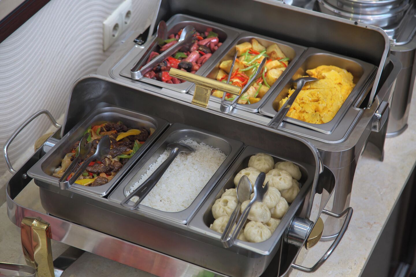 A buffet with various food options including rice, meat dishes, and dumplings.