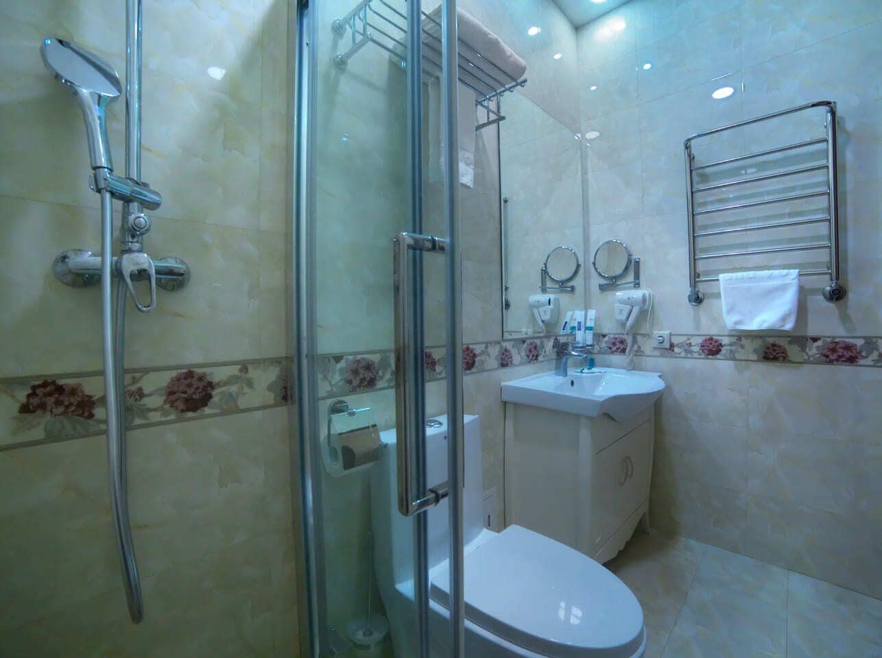A bathroom with a glass-enclosed shower, a toilet, and a sink.