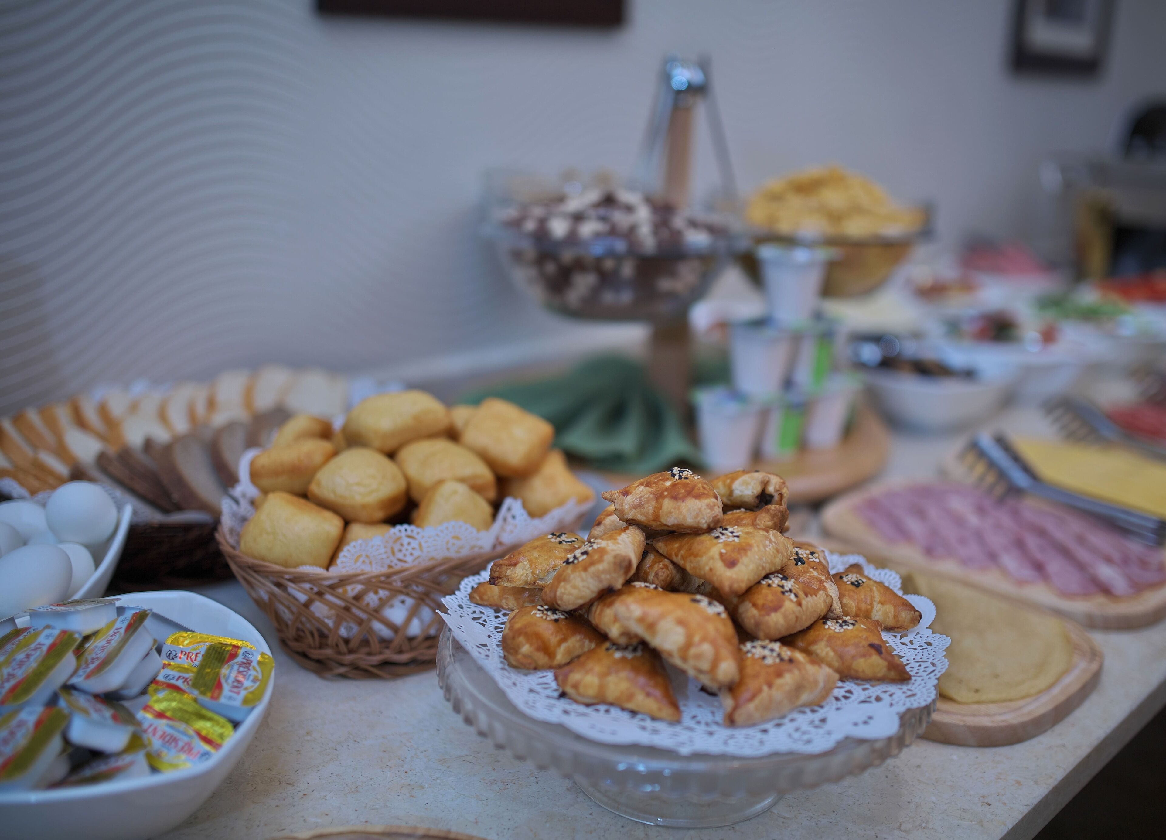 Un tavolo per buffet con diversi cibi, tra cui pasticceria, pane e una ciotola di uova.