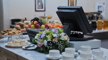Una mesa de buffet con diferentes platillos, un centro de mesa floral y un monitor de computadora.