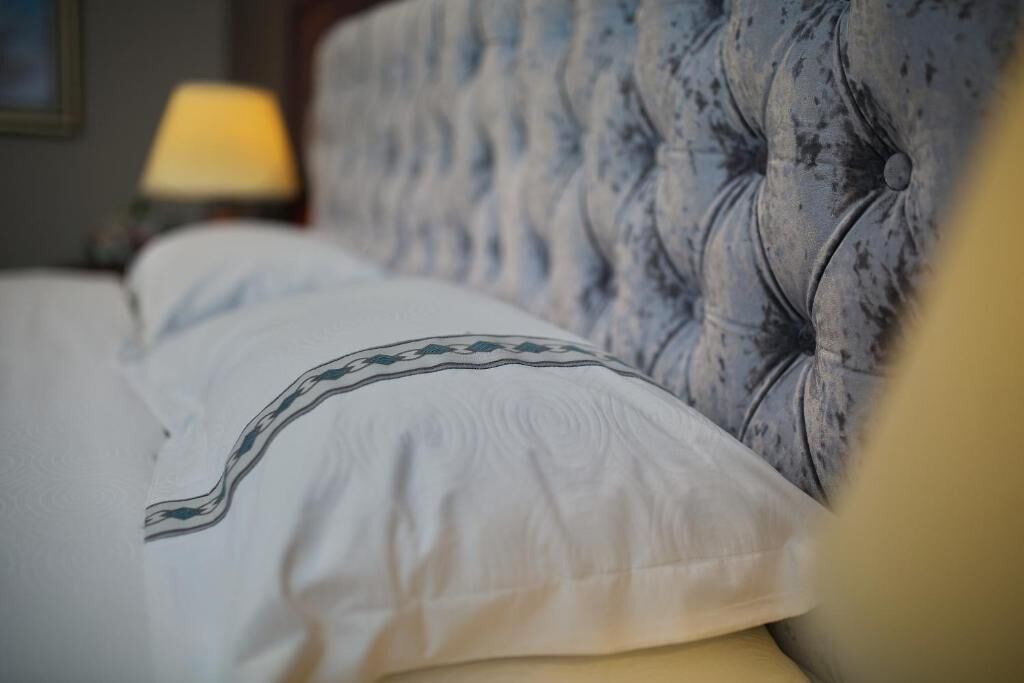A bed with a tufted headboard and a patterned pillow.