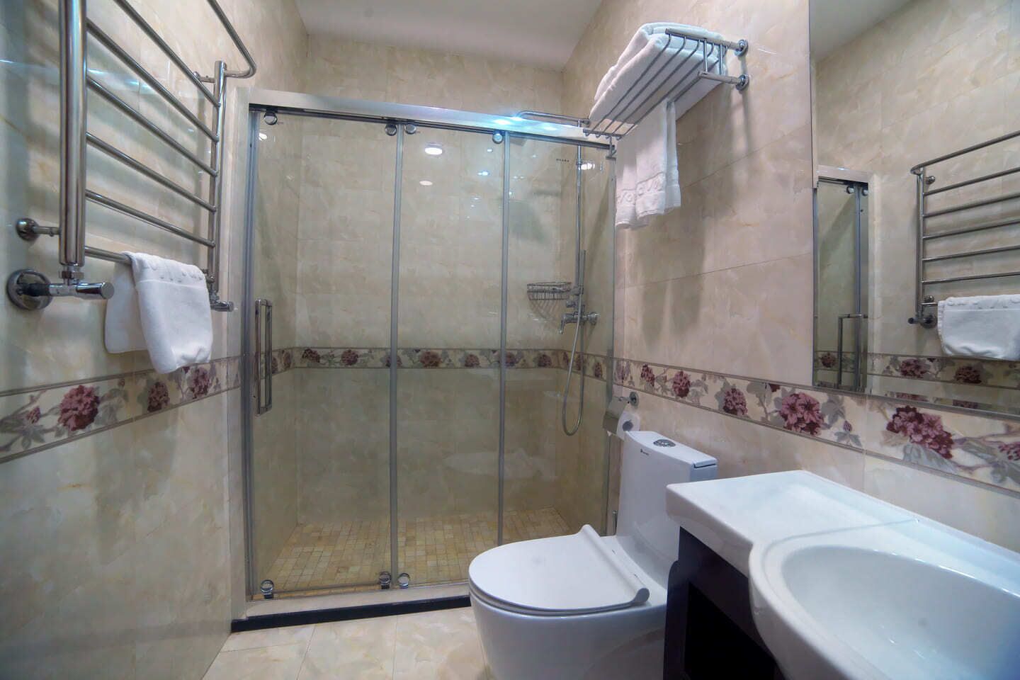 A bathroom with a glass-enclosed shower, a toilet, and a sink.