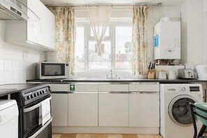 Eine kompakte Küche mit Mikrowelle, Backofen und Waschmaschine.