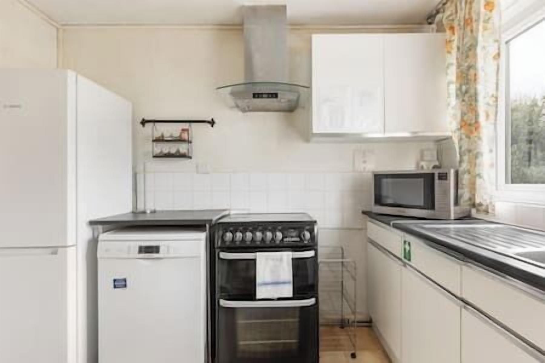 A kitchen with a stove, microwave, and white cabinets.