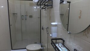 Et badeværelse med bruseniche, toilet og håndvask med sæbedispenser.
