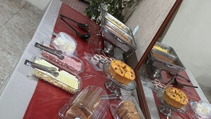 En buffet med et udvalg af madvarer, herunder frugt, brød og desserter.