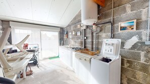 Una cocina con estufa a gas, calentador de agua y un lavamanos.
