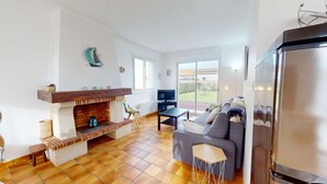 Una sala de estar con chimenea, un sofá, un televisor y un ventanal con vistas al exterior.