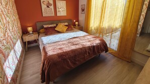 Ein Schlafzimmer mit einem großen Bett, einem Nachttisch mit Lampe und einem Fenster mit Vorhängen.