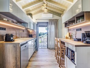 Una cocina moderna con armarios de madera, horno empotrado y un espacio para café.
