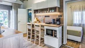 A compact kitchen with a built-in oven, a coffee maker, and a small dining area with two chairs. - Villa Pine Trees bei Kardous, Skopelos Privater Pool by Interhome (Skopelos)