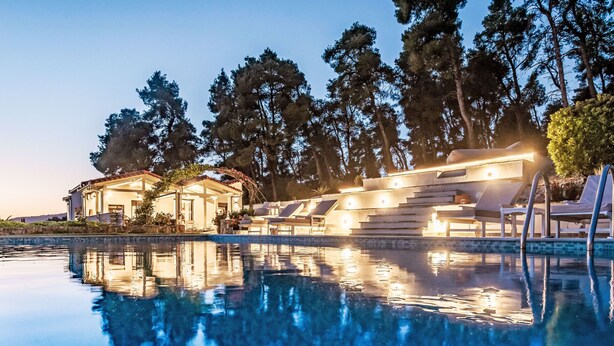 A swimming pool with lounge chairs and a building with a covered patio. - Villa Pine Trees bei Kardous, Skopelos Privater Pool by Interhome (Skopelos)