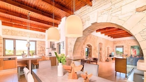 A spacious kitchen with a large island, stone walls, and wooden beams. - "Acrothea Villa Beheizter Pool" by Interhome (Georgioupoli)