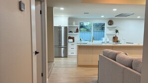 A modern kitchen with a built-in refrigerator, a wooden countertop, and a window overlooking a blue fence. - Private Luxury Oasis – Fully Renovated with Huge Backyard (Mission Viejo)