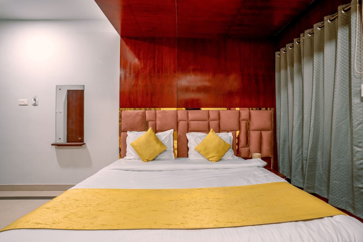 A hotel room with a large bed, a wooden headboard, and a yellow accent runner.