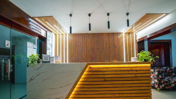 Un área de recepción con mostrador de mármol, listones de madera y lámparas colgantes.