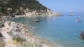 Un paysage côtier avec des eaux limpides, des rivages rocheux et un voilier.