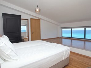 A bedroom with a large bed, a wardrobe, a mirror, and a view of the sea through large windows. - "Capro" mit Infinity-Pool by Interhome (Vafkeri)