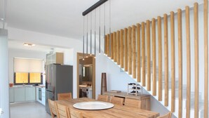 Une cuisine moderne avec une table et des chaises en bois, un escalier avec des rampes en bois, et une vue sur l’espace de vie.