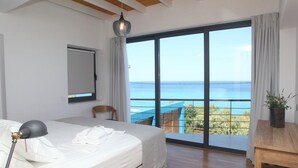 Une chambre avec un grand lit, un bureau et une vue sur l’océan.