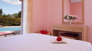 Un dormitorio con cama, una mesita de noche con un florero, un espejo y vistas a una piscina.