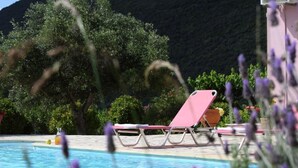 Zona de piscina con sillones de descanso y montañas al fondo.