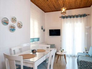 A modern living room with a dining area, featuring a wooden ceiling, a TV mounted on the wall, and decorative plates on the wall. - Zwei-Zimmer-Wohnung mit atemberaubender Aussicht by Interhome (Kalami)