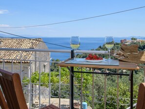 En balkon med et bord dækket til to, ud til et kystlandskab.