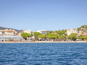 Eine Küstenstadt mit Strand, Gebäuden und Bäumen.