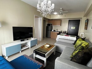 Ein Wohnzimmer mit Fernseher, Sofa, Couchtisch und einer Deckenleuchte.