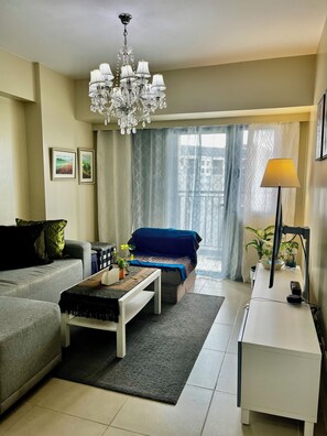 Ein modernes Wohnzimmer mit grauem Sofa, blauem Sofa, weißem Couchtisch, einer Chandelieber und einer Stehlampe.