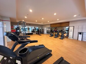 Ein Fitnessstudio mit Laufbändern, Kraftgeräten und einer Spiegelwand.
